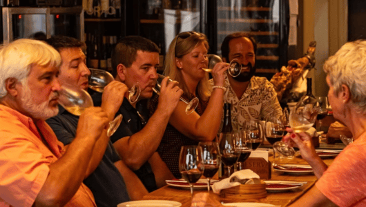 Group of people seated at a bar, tasting wine.