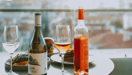 Wine and glasses on a table with a blurred city view.