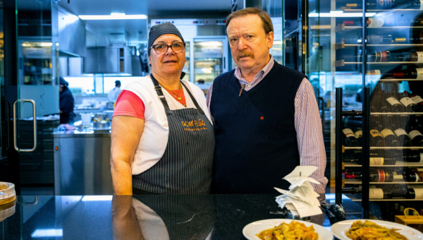 A man and a woman stand together in a restaurant kitchen.