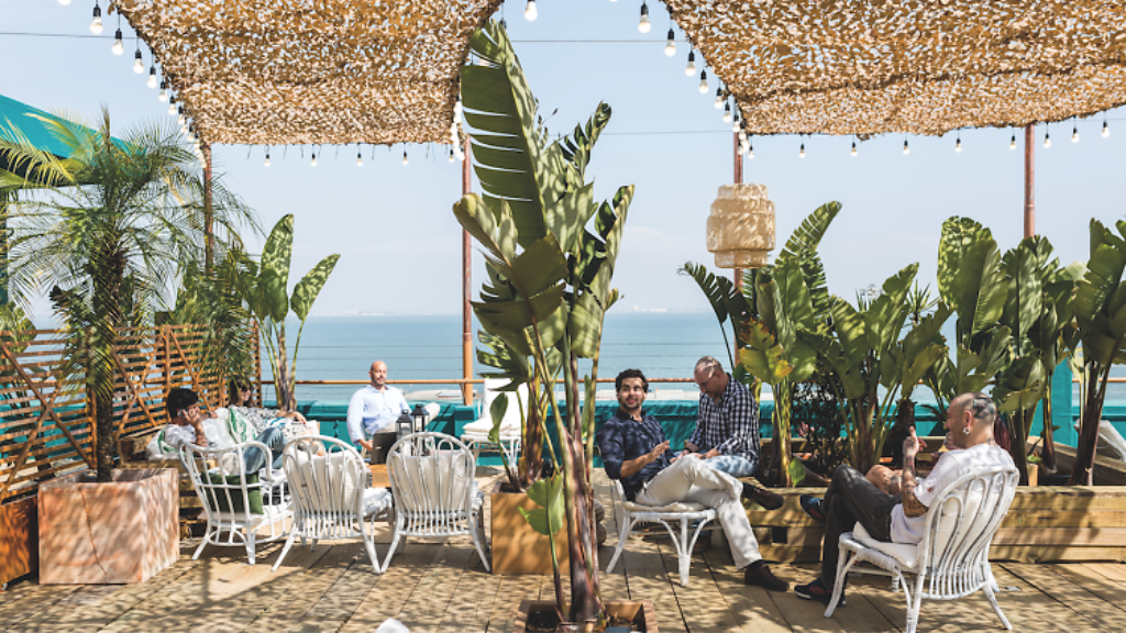 a group of people sitting at a table with an umbrella