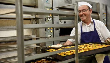A pastry chef with a tray of cream custards