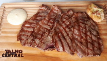 a piece of meat on a cutting board with a cake