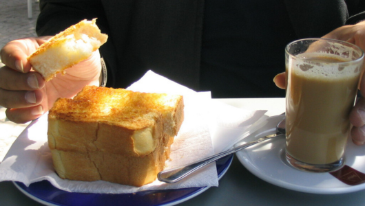 a half eaten sandwich on a plate next to a cup of coffee