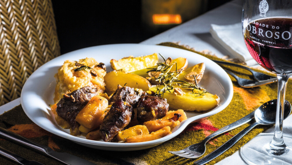 00.Évora travel guide for food lovers_feat photo Plate of beef, potatoes, carrots, and mashed potatoes with a glass of red wine.