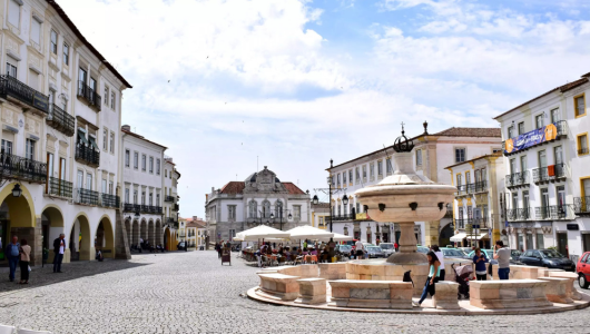 Historic town square with a central fountain and surrounding buildings.