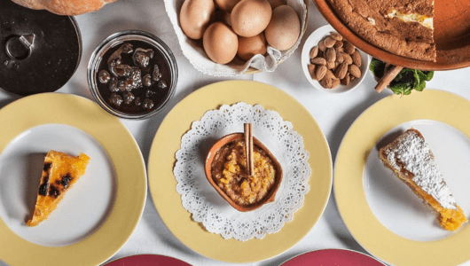 Various plates with desserts, eggs, and almonds on a table.