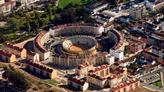 Aerial view of a circular bullring surrounded by buildings in a city.