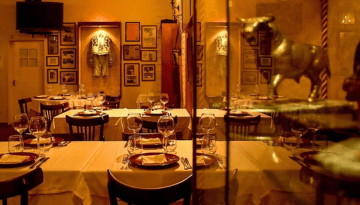 Cozy restaurant with tables set, bull statue, and wall memorabilia.