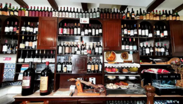 Restaurant shelves filled with wine bottles, cured meats, and deli items.
