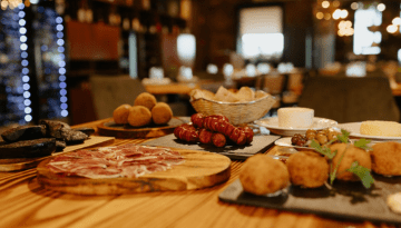 Assorted tapas on a wooden table in a dimly lit restaurant.