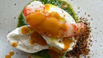 Plated dish with shrimp, whipped cream, green sauce, and crumbled seasoning on a white plate.