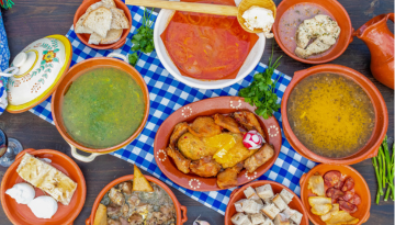 Assorted traditional dishes in clay pots on a blue checkered tablecloth.