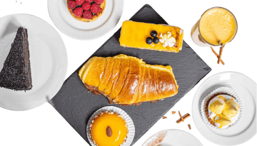 Assorted pastries and desserts, including croissant and cakes, arranged on a slate and plates.