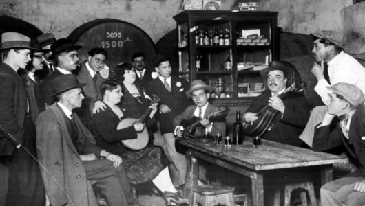 Group of people in vintage attire playing music and socializing in a rustic bar setting.