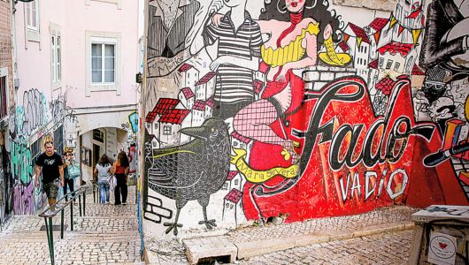 Colourful street mural with people, crow, and 'Fado Vadio' in letters.
