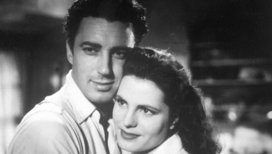 Black and white image of a man and woman embracing, with the woman smiling slightly.
