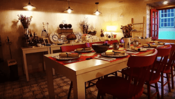 Warmly lit dining room with set table, red chairs, decorative plates, and vases on shelves.