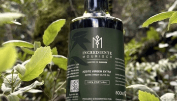 Olive oil bottle labeled 'Ingrediente Mourisco' surrounded by green leaves.