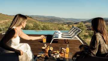 Two women enjoying a poolside picnic with a scenic mountain view.