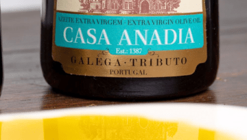 Close-up of Casa Anadia olive oil bottle label on wooden table.