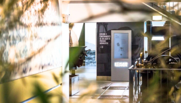 Hallway with a digital display screen and blurred plants in the foreground.