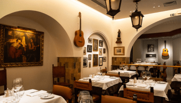 Cozy restaurant with white tablecloths, guitars on walls, and warm lighting.