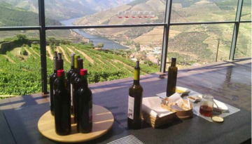 Wine bottles on a table with a vineyard and river view.