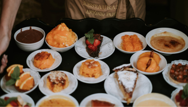 Tray of various desserts in white bowls and plates, including cakes, mousses, and fruit.