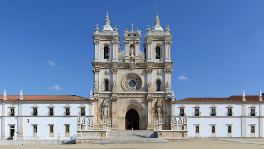 Front view of a historic monastery with twin towers and a central rose window.