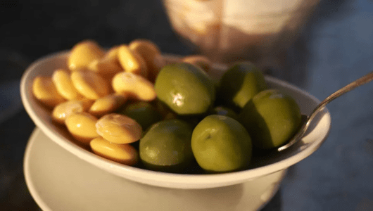 Plate with green olives and yellow lupini beans.