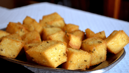 Plate of crispy golden cubes of fried polenta on a table.