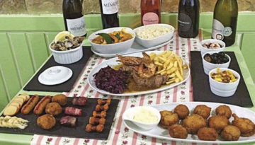 Assorted appetizers and wine bottles on a table with a floral tablecloth.