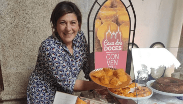 Smiling person holding a tray of pastries next to a 'Casa dos Doces' sign.