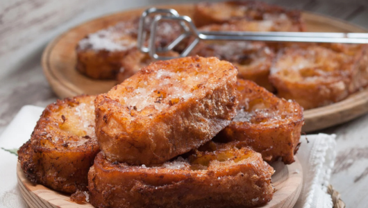 Close-up of sugared French toast slices on wooden plates.