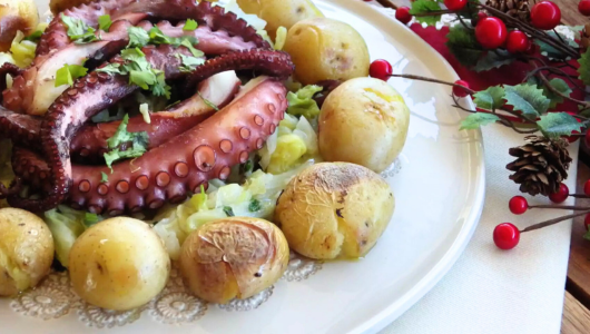 Octopus and potatoes on a plate with festive decor nearby.