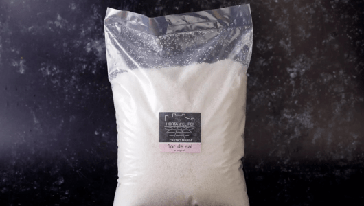 The story of salt in Portugal - Bag of flor de sal salt against dark background.