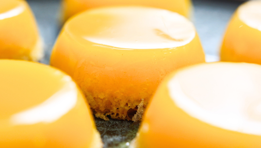 Close-up of yellow glazed desserts with smooth tops on a tray.