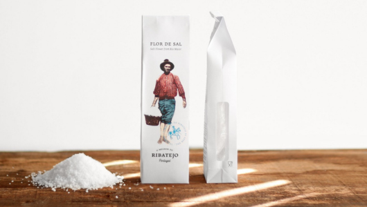 The story of salt in Portugal - Salt packaging and pile on wooden surface against white background.