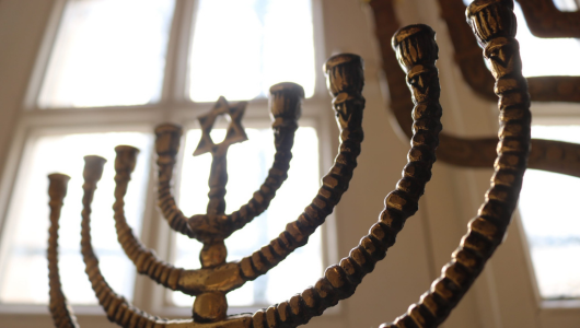 Close-up of a menorah with a Star of David, in front of a bright window.