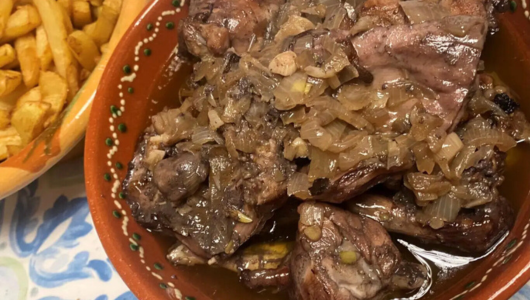 Cooked meat with onions in a bowl, fries on the side