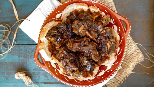 Traditional Mexican dish in brown sauce on a decorative plate, surrounded by fabric and rope accents.