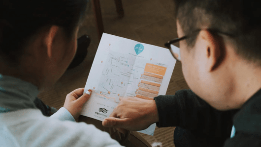 Two people examining a map or brochure indoors.