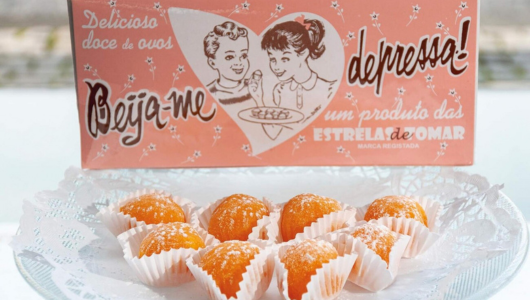 Box of sweets with vintage design behind plate of orange confections on lace doily.