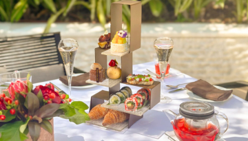 Gourmet afternoon tea set with pastries and tea on an outdoor table.