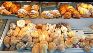 Assorted breads and pastries displayed in a bakery case.