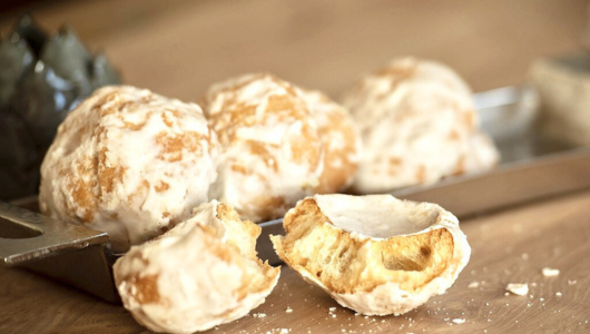 Four iced cookies with one broken, on a rectangular metal tray on a wooden surface.