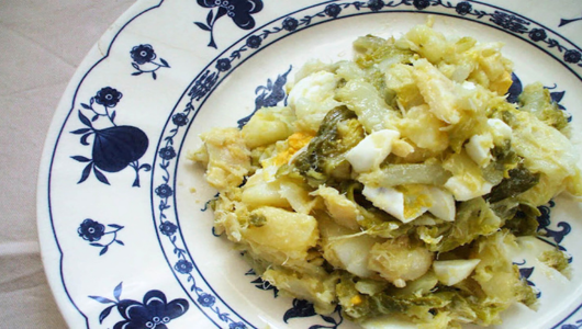 Plate with food mixture including potatoes and greens on a patterned plate.