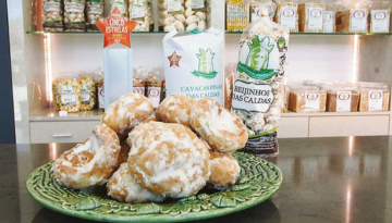 Glazed pastries on a green plate with various packaged snacks in the background.