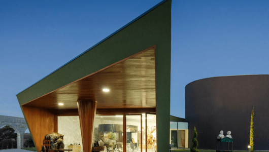Modern building with angular roof and large glass windows at twilight.