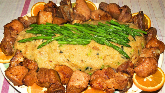 Roast surrounded by meat chunks, garnished with asparagus and orange slices.